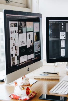 A sleek modern office setup featuring dual monitors, Apple devices, and creative decor in an indoor workspace.