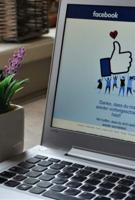 A Lenovo laptop displaying Facebook login beside a lavender plant indoors.